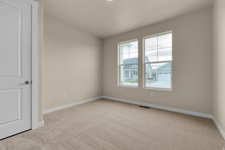 Empty room with light colored carpet and baseboards