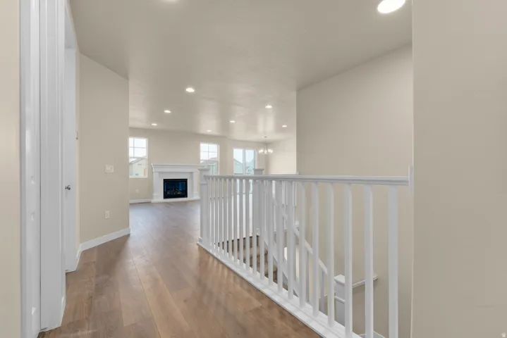 Hall featuring wood-type flooring, an upstairs landing, and suspended lighting