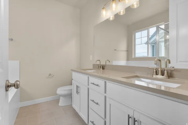 Bathroom with double vanity and light tile patterned floors