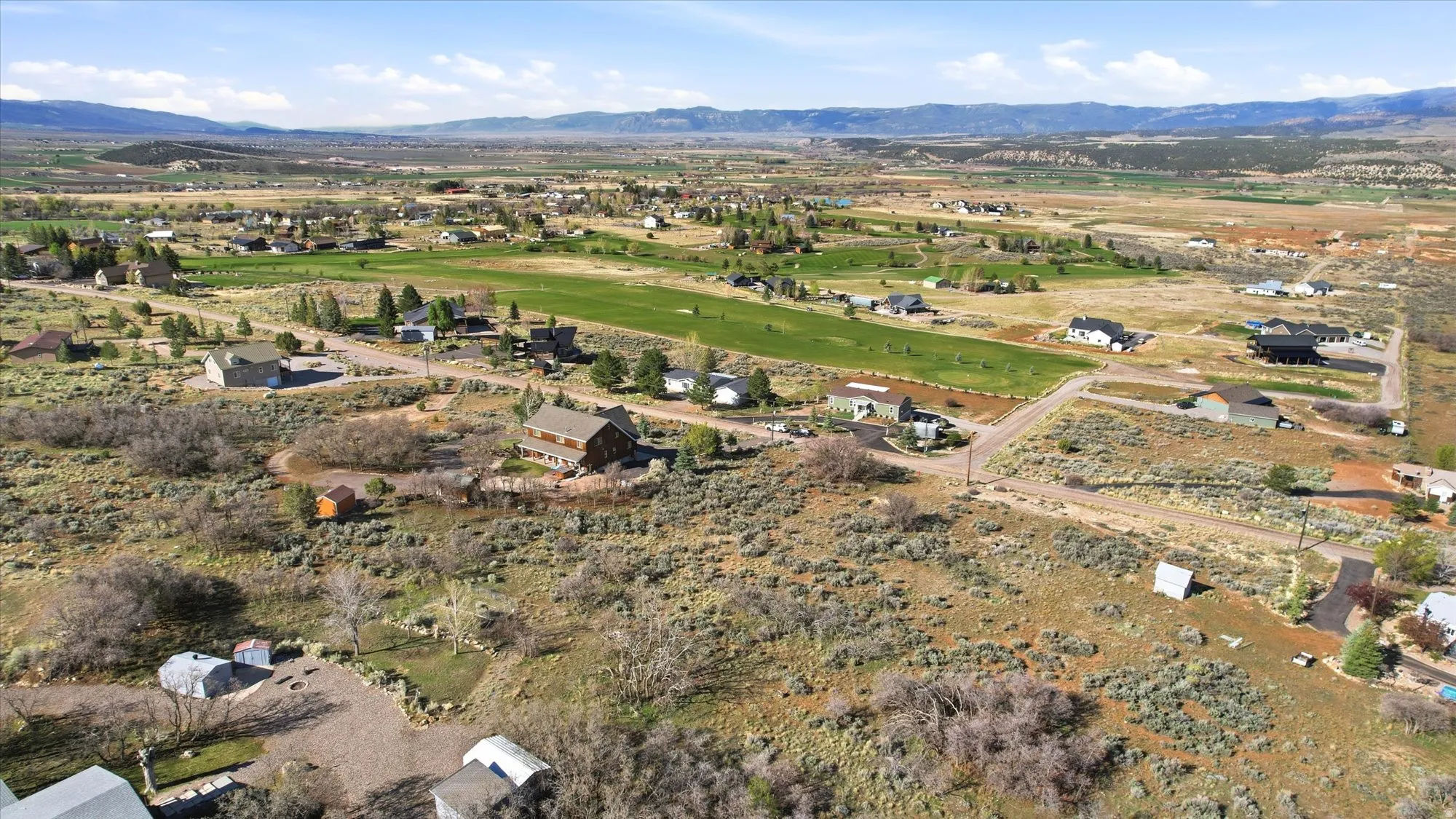 Expansive landscape with scattered residential properties and distant mountain ranges