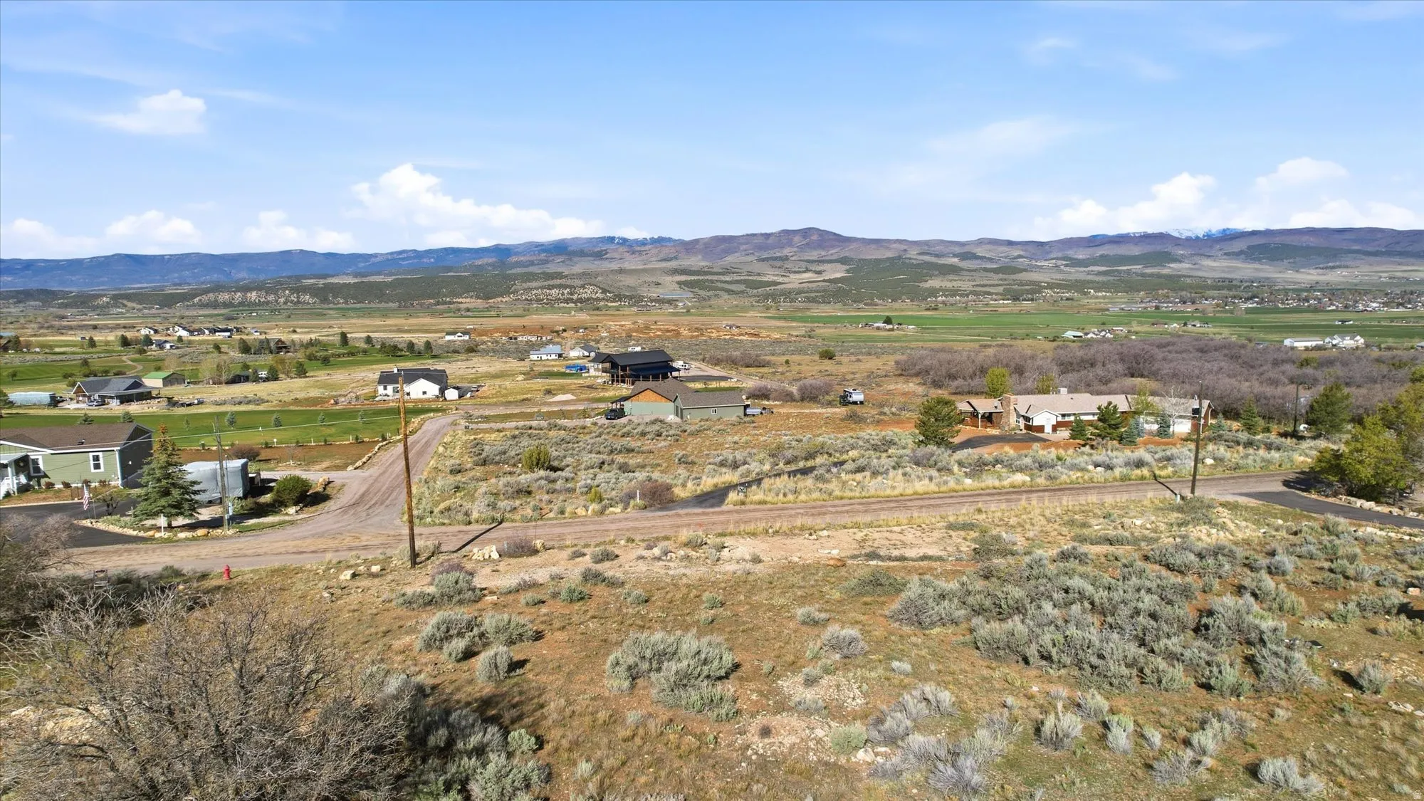 Expansive undeveloped land featuring natural shrubbery and distant mountain ranges