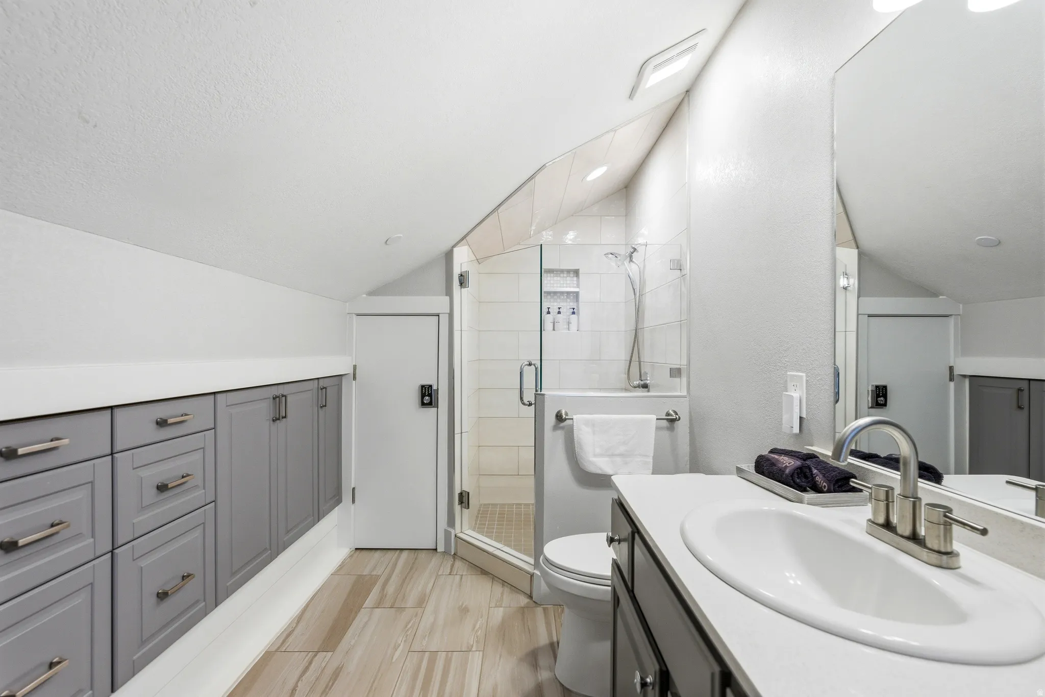 Full bathroom with vaulted ceiling, vanity, and a stall shower