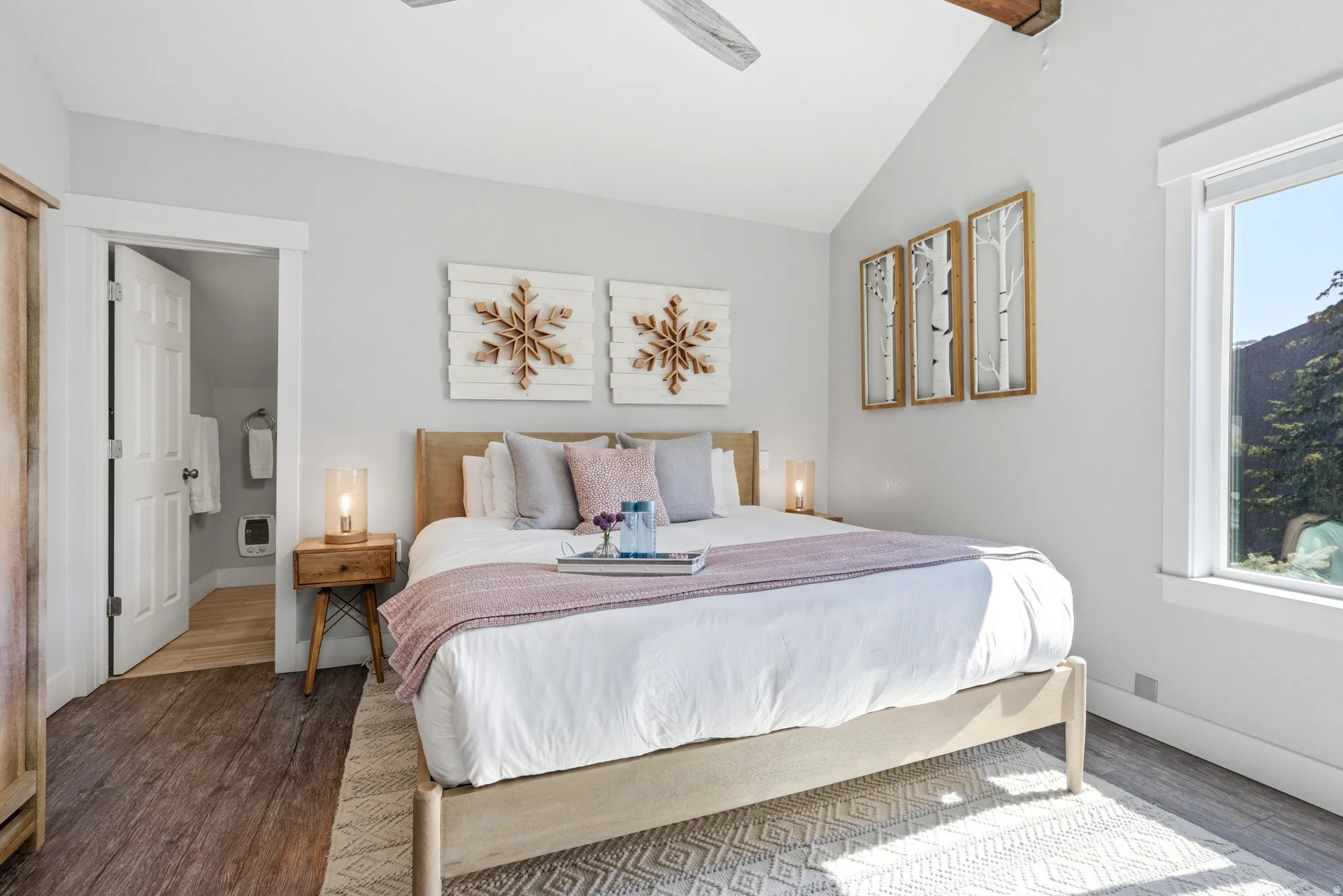 Bedroom with wood finished floors, ensuite bath, lofted ceiling, a ceiling fan, and heating unit