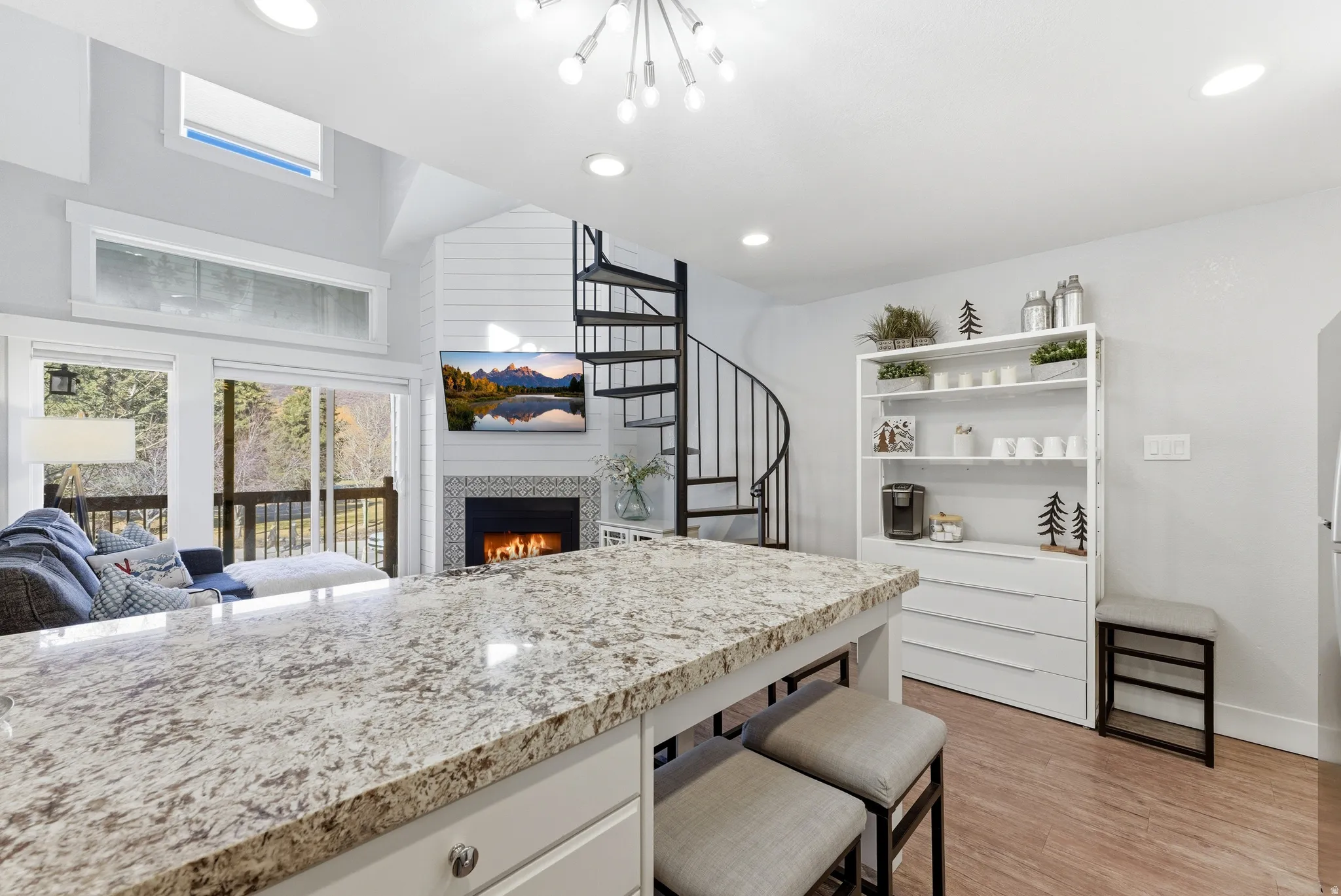 Kitchen featuring light stone counters, a warm lit fireplace, white cabinets, light wood-style floors, and open floor plan