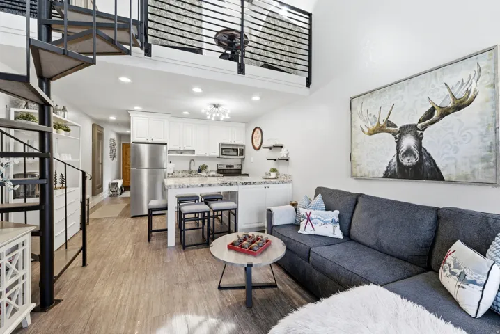 Living room with a high ceiling, light wood-type flooring, and recessed lighting