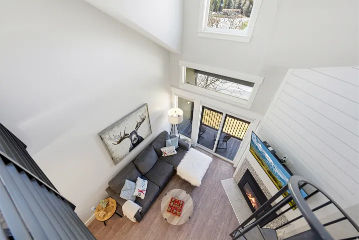 Living room featuring a tile fireplace, wood finished floors, and a high ceiling