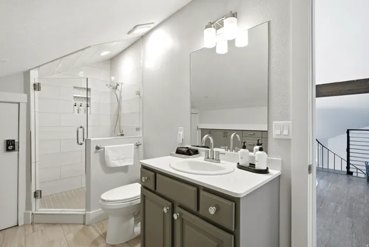 Full bath with vanity, lofted ceiling, a stall shower, and light wood-style floors