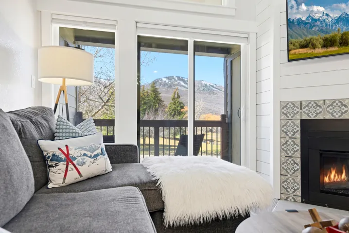 Bedroom featuring a mountain view, a fireplace, access to exterior, multiple windows, and wooden walls