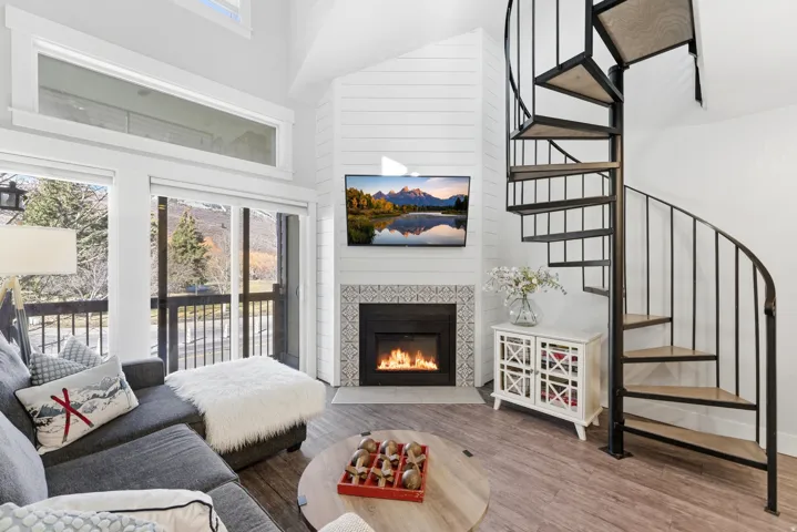 Living room with a high ceiling, a fireplace, wood finished floors, and plenty of natural light