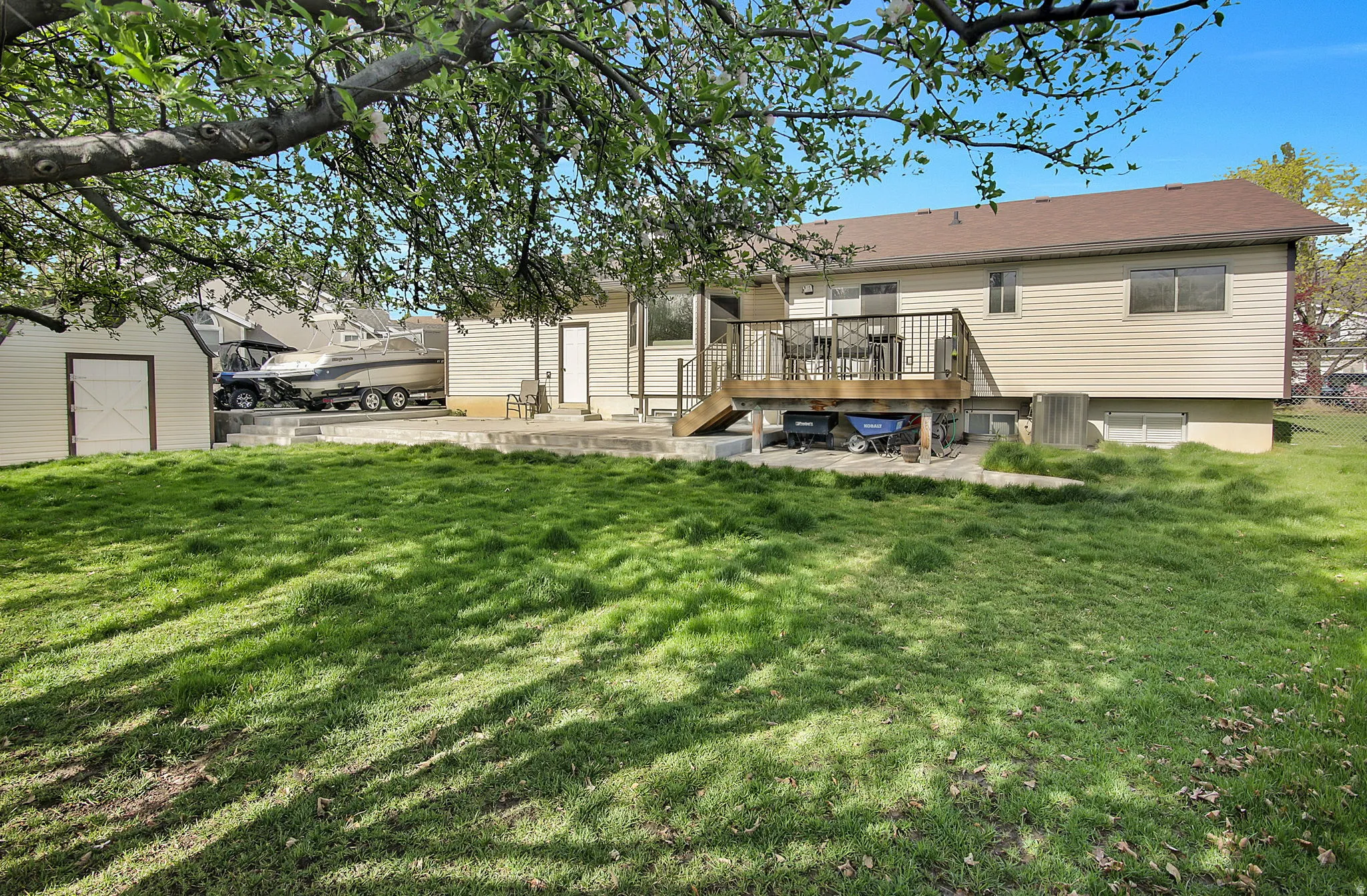 Rear view of house featuring a wooden deck, a yard, a patio, and an outdoor structure