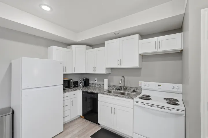 Kitchen featuring white appliances, white cabinetry, and light wood-type flooring