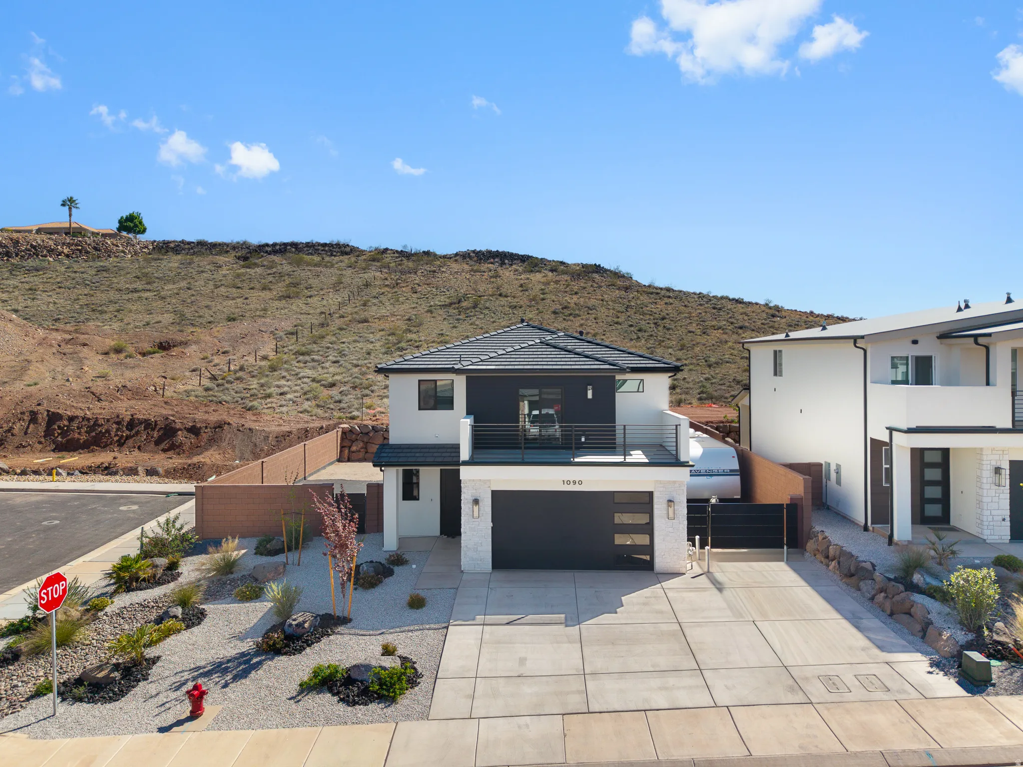 Modern home with an attached garage, stucco siding, concrete driveway, a patio, and a mountain view