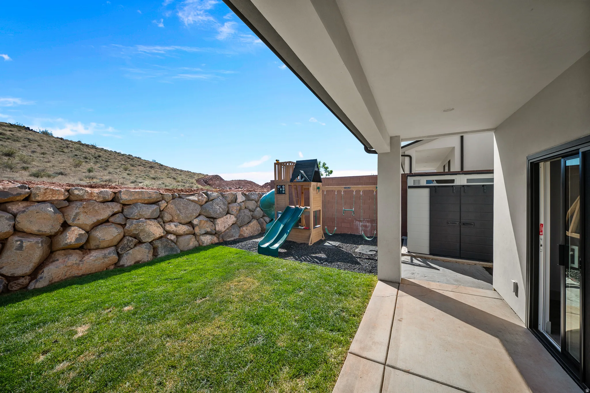 Fenced backyard with a patio and a playground
