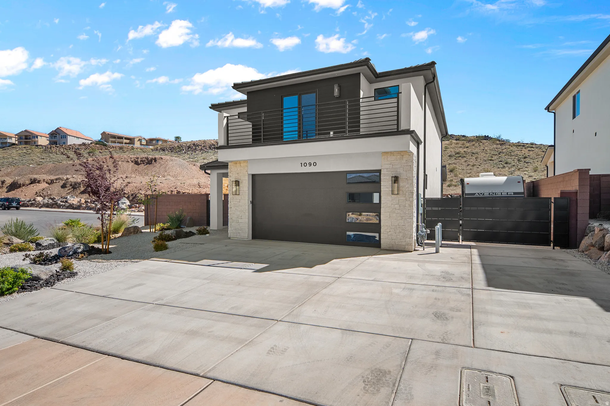 View of front of home featuring a balcony, an attached garage, concrete driveway, a gate, and stucco siding
