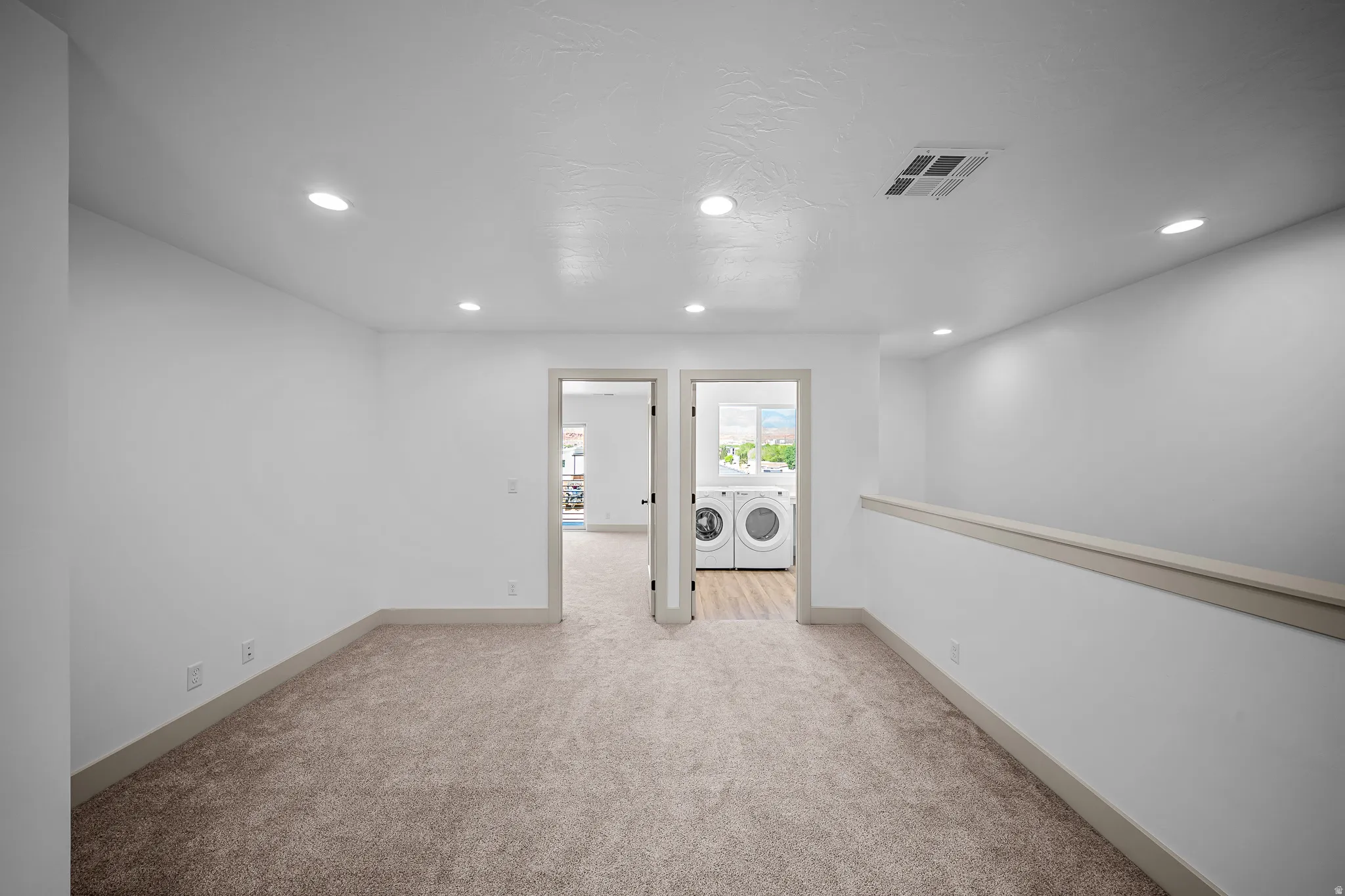 Unfurnished room with light carpet, washer and dryer, and recessed lighting