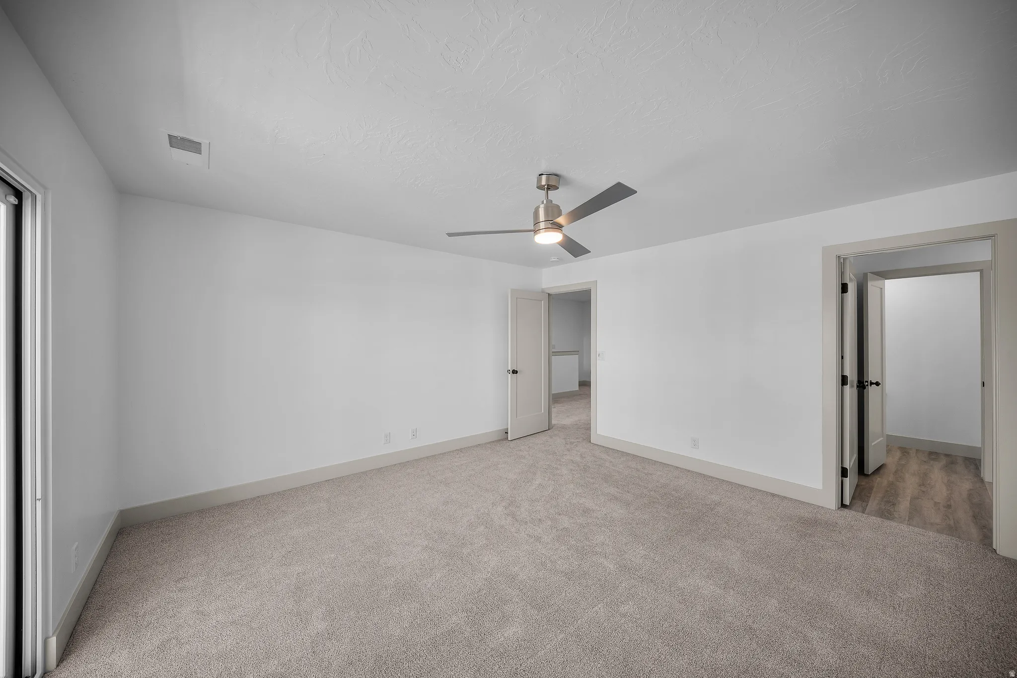 Unfurnished bedroom with light carpet and a ceiling fan