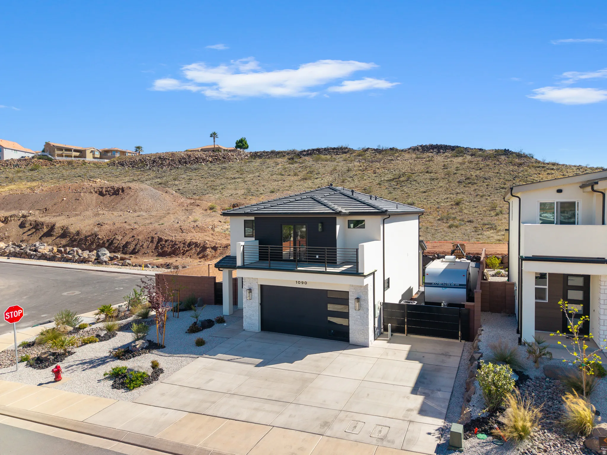 Contemporary house featuring an attached garage, driveway, stucco siding, a balcony, and stone siding