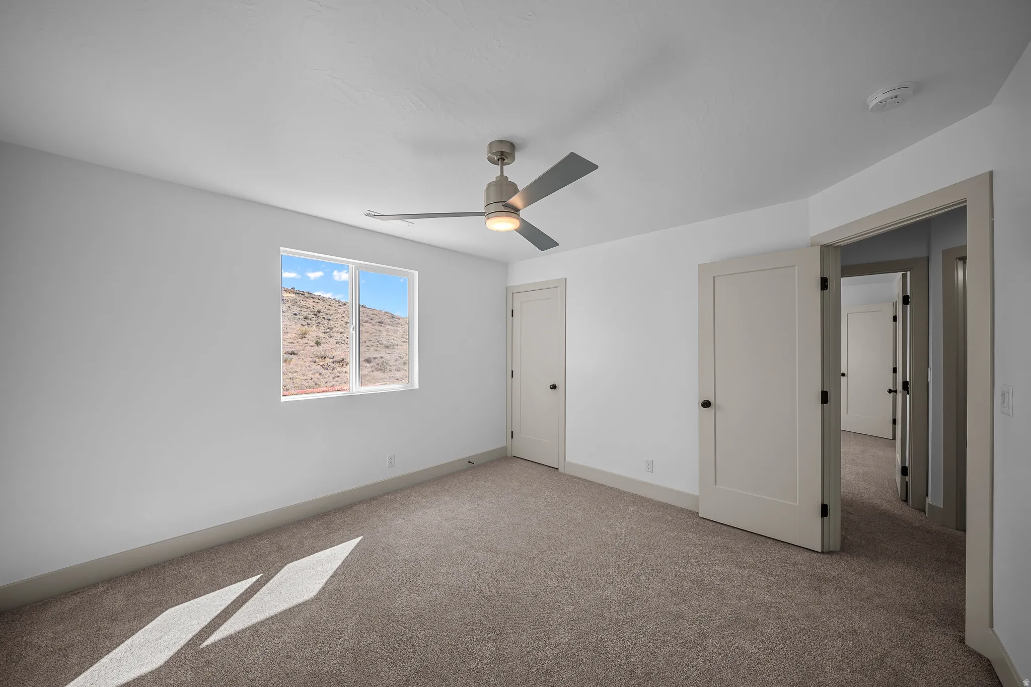 Unfurnished bedroom featuring light carpet and ceiling fan