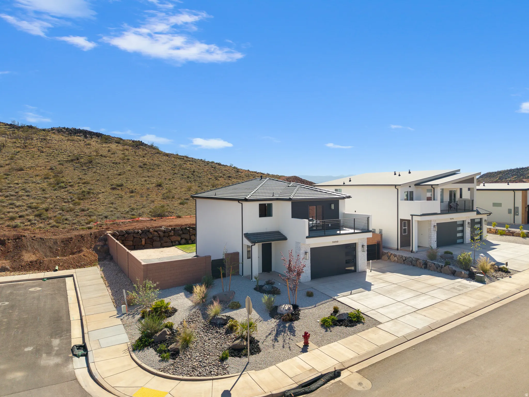 Contemporary home with a garage, stucco siding, concrete driveway, and a balcony