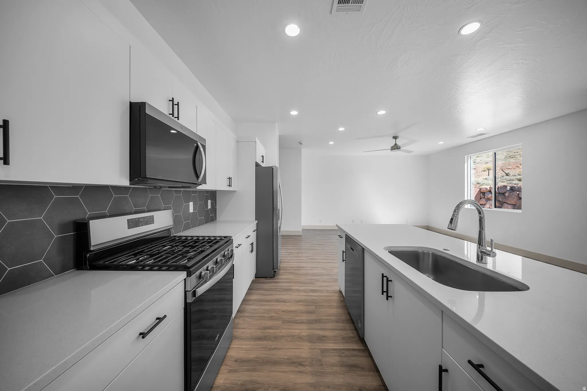 Kitchen featuring stainless steel appliances, white cabinets, dark wood-style flooring, recessed lighting, and light stone countertops