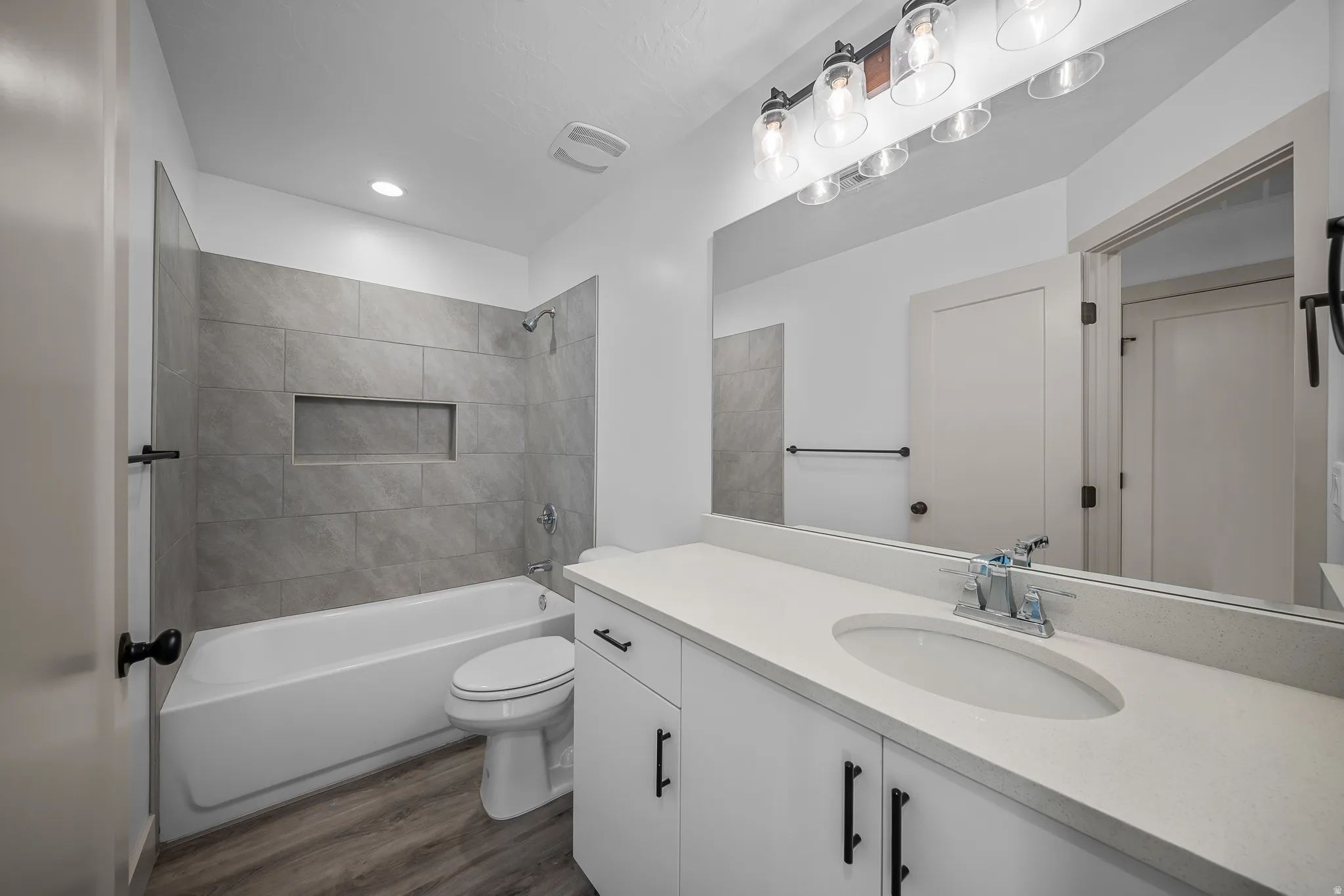 Full bath featuring vanity, bathtub / shower combination, and dark wood-type flooring