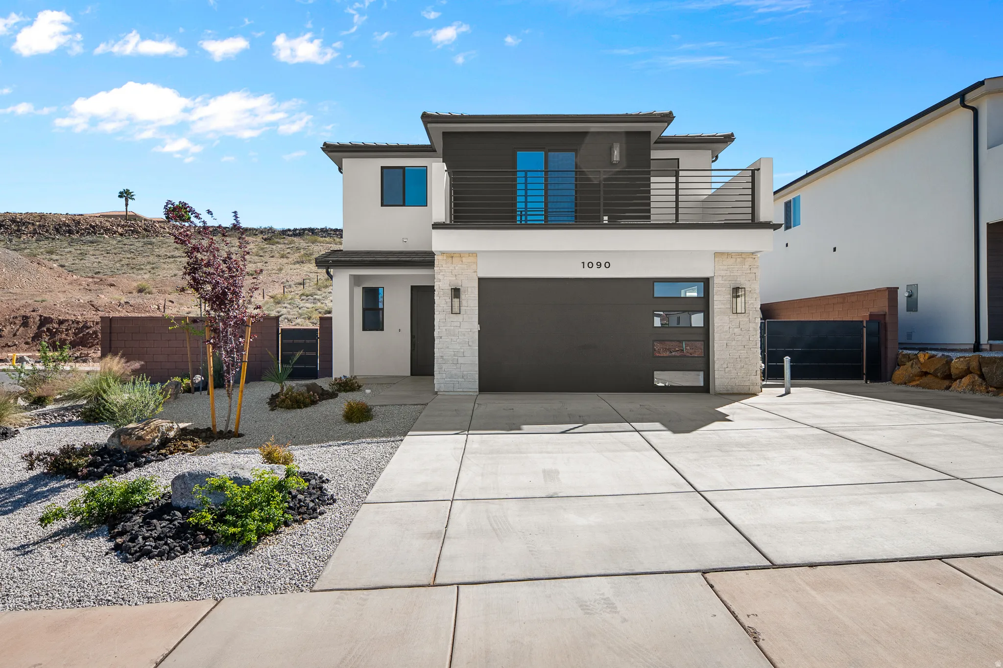 Contemporary home with stucco siding, a balcony, a garage, and concrete driveway