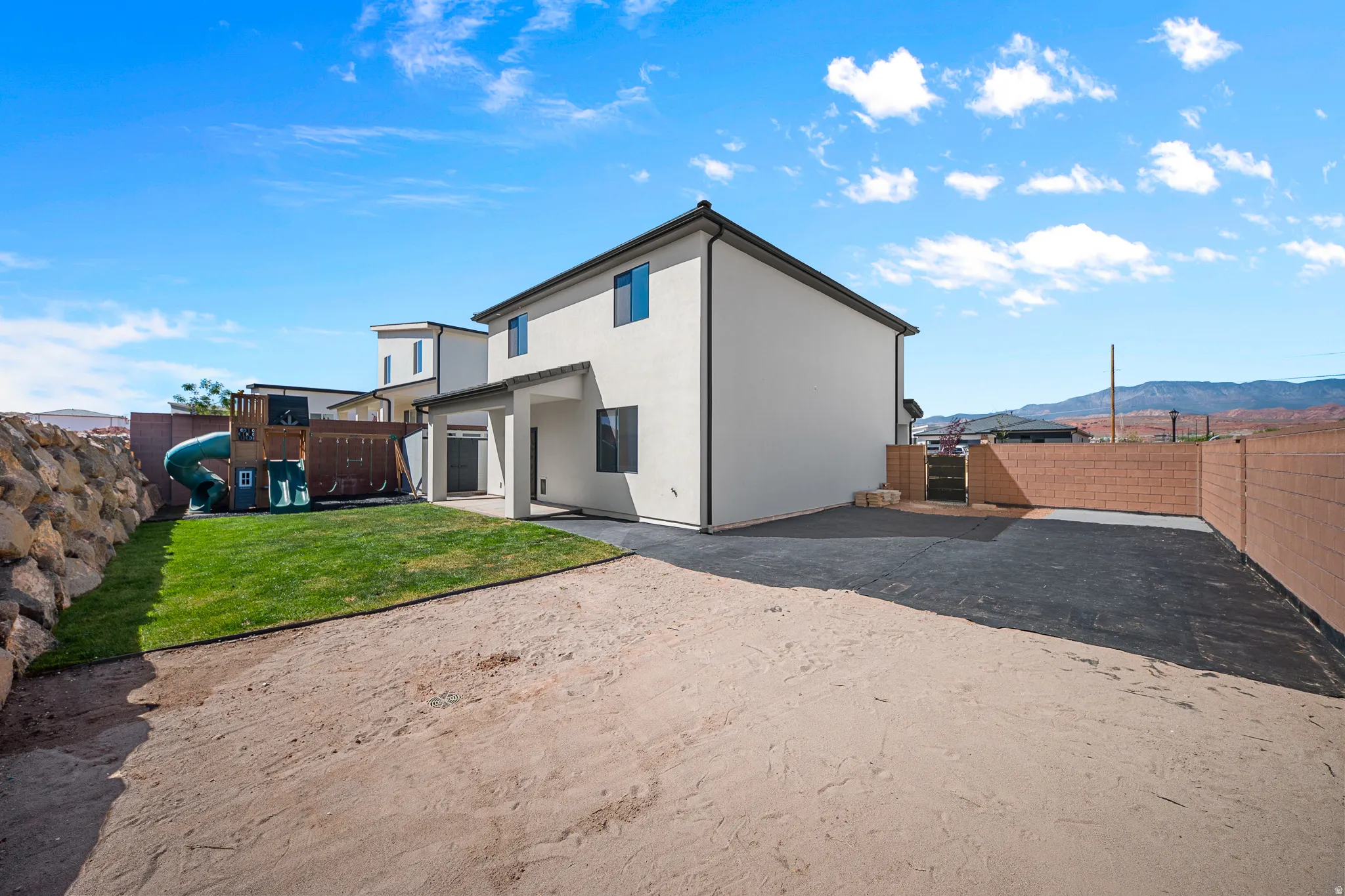 Rear view of property with a mountain view, a patio, a fenced backyard, and stucco siding