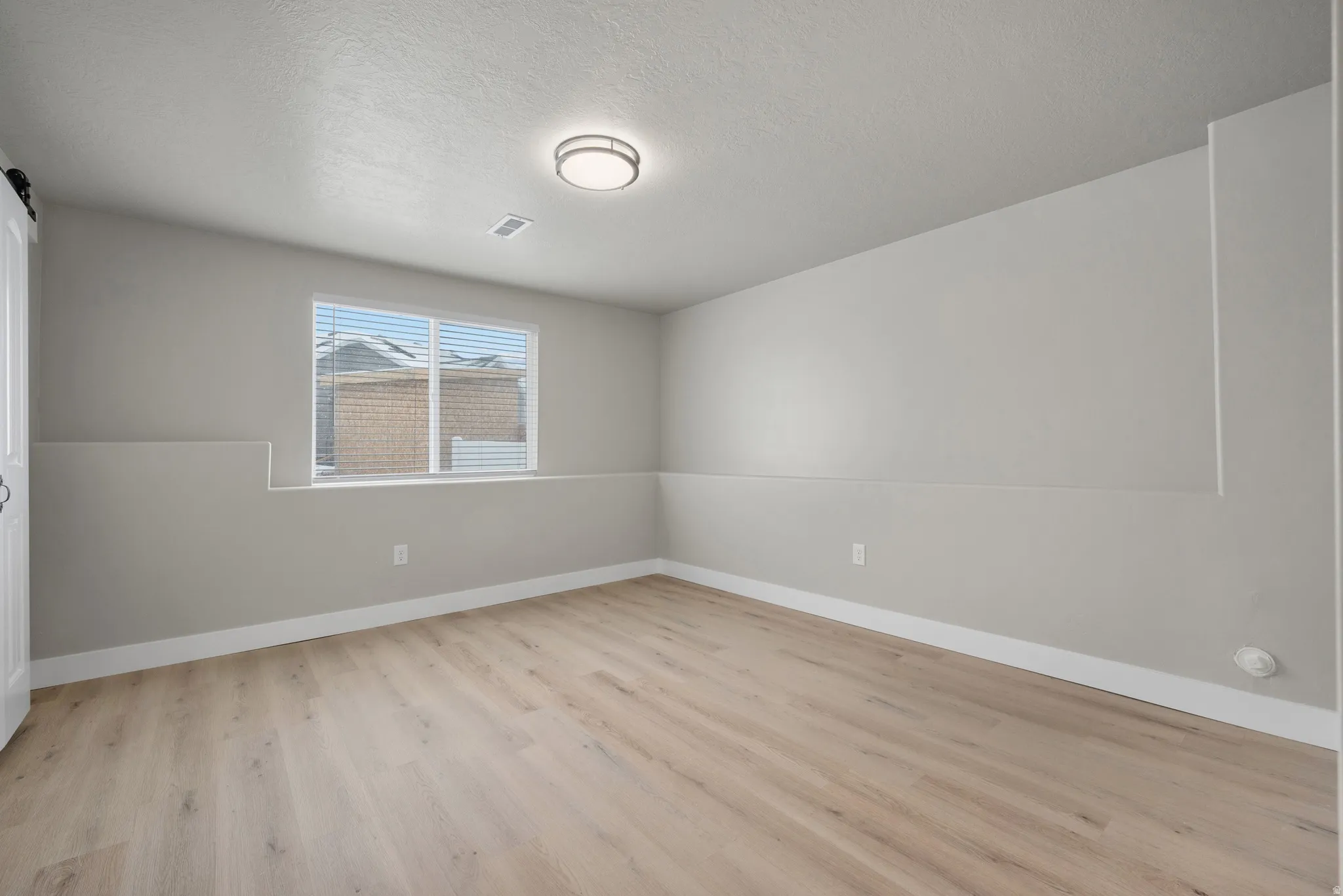 Spare room with light wood finished floors and a textured ceiling