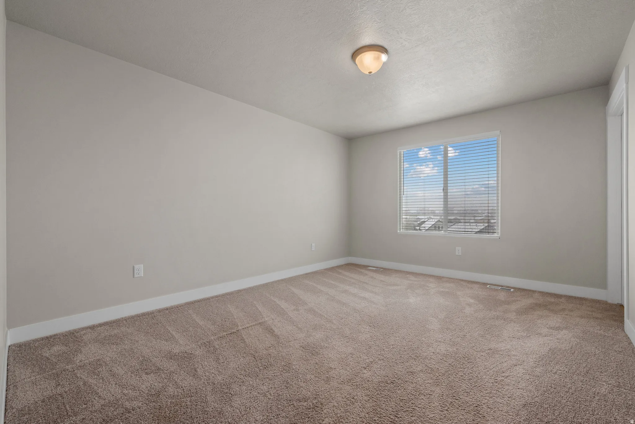 Empty room featuring light carpet and a textured ceiling