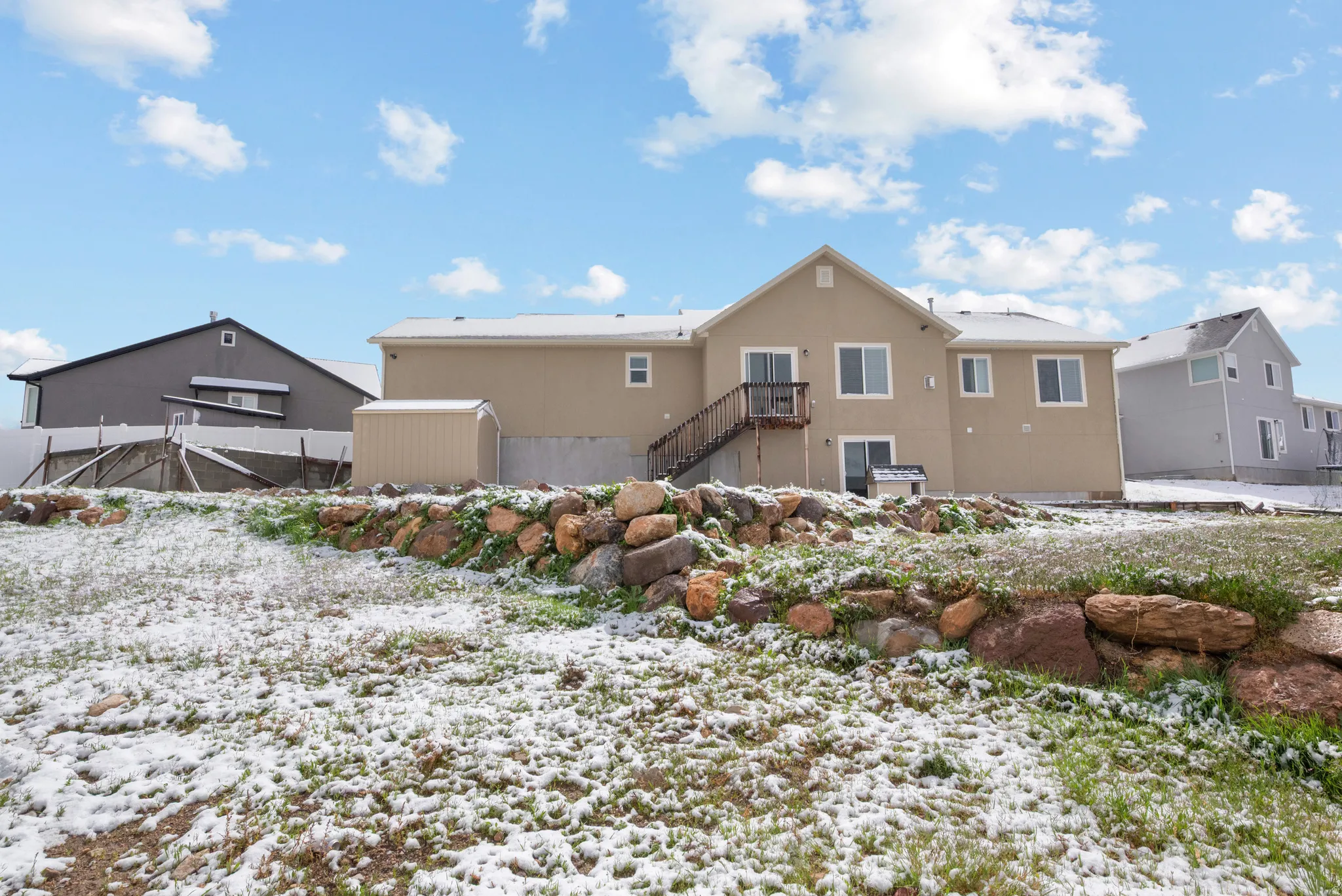 Snow covered house featuring stucco siding and stairway