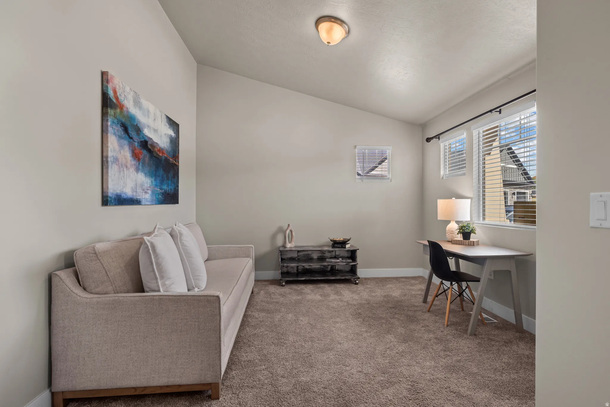 Carpeted room featuring a sloped ceiling, light-toned walls, and a window with horizontal blinds