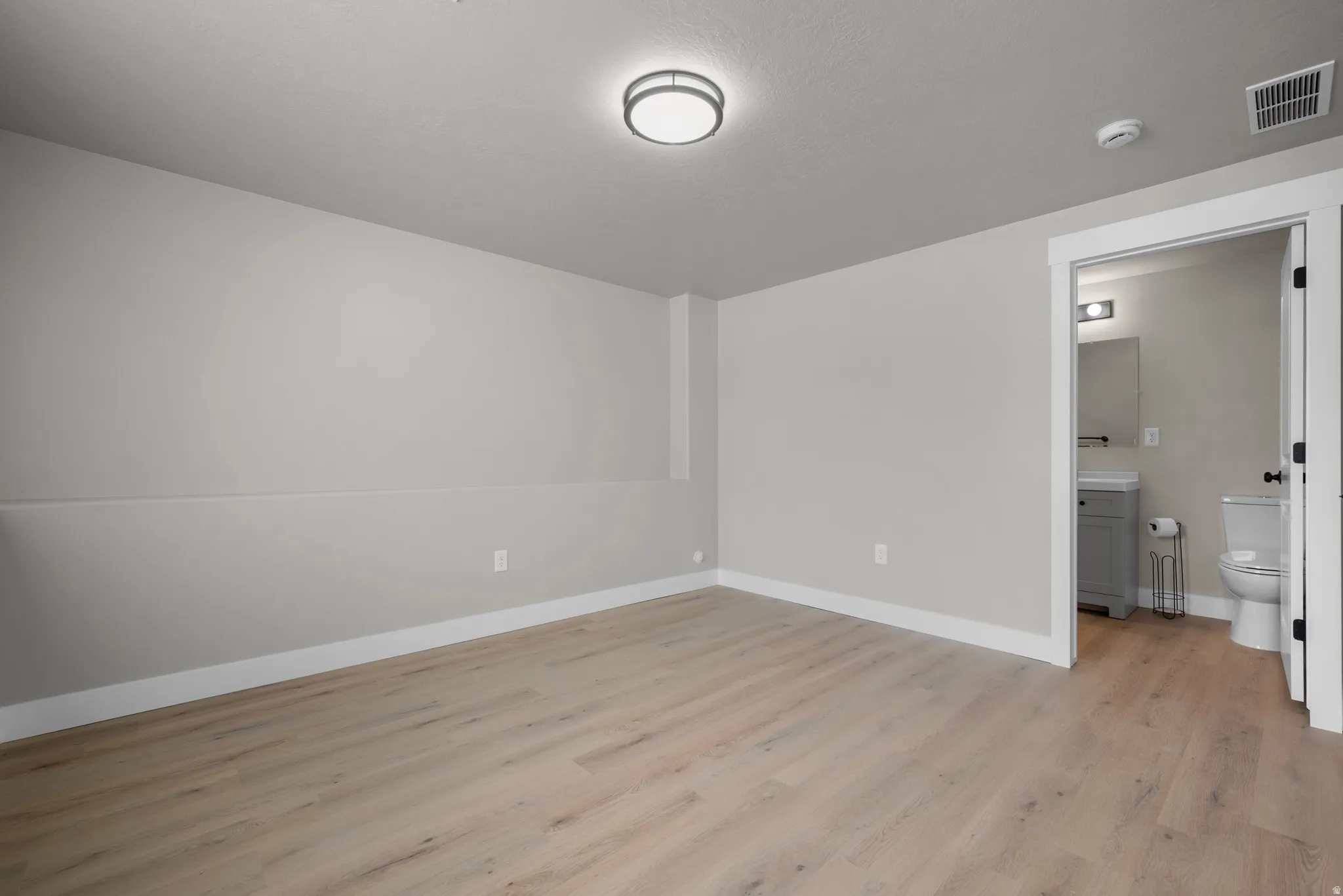 Unfurnished bedroom with light wood finished floors and baseboards