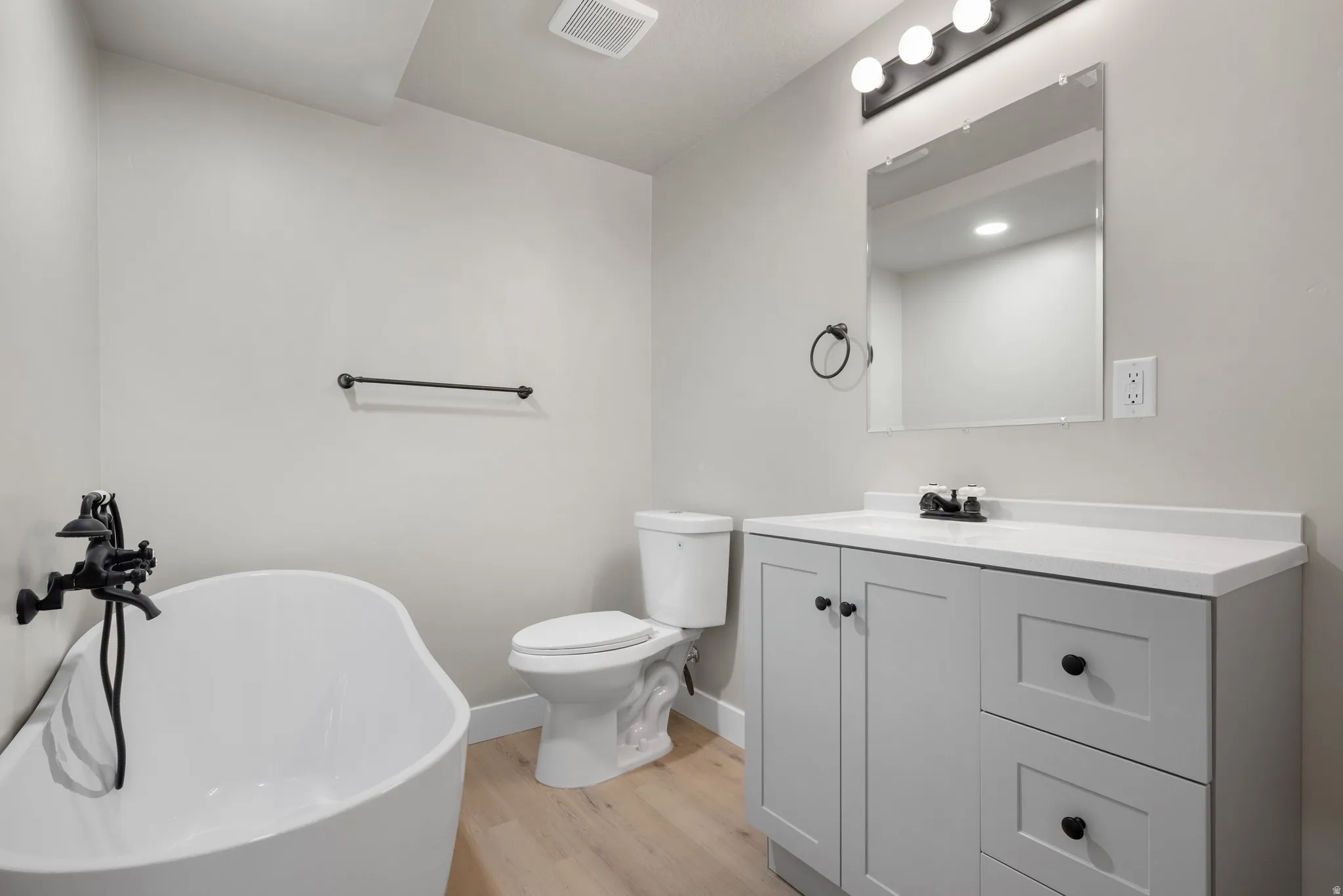 Bathroom with vanity, light wood finished floors, and a freestanding bath