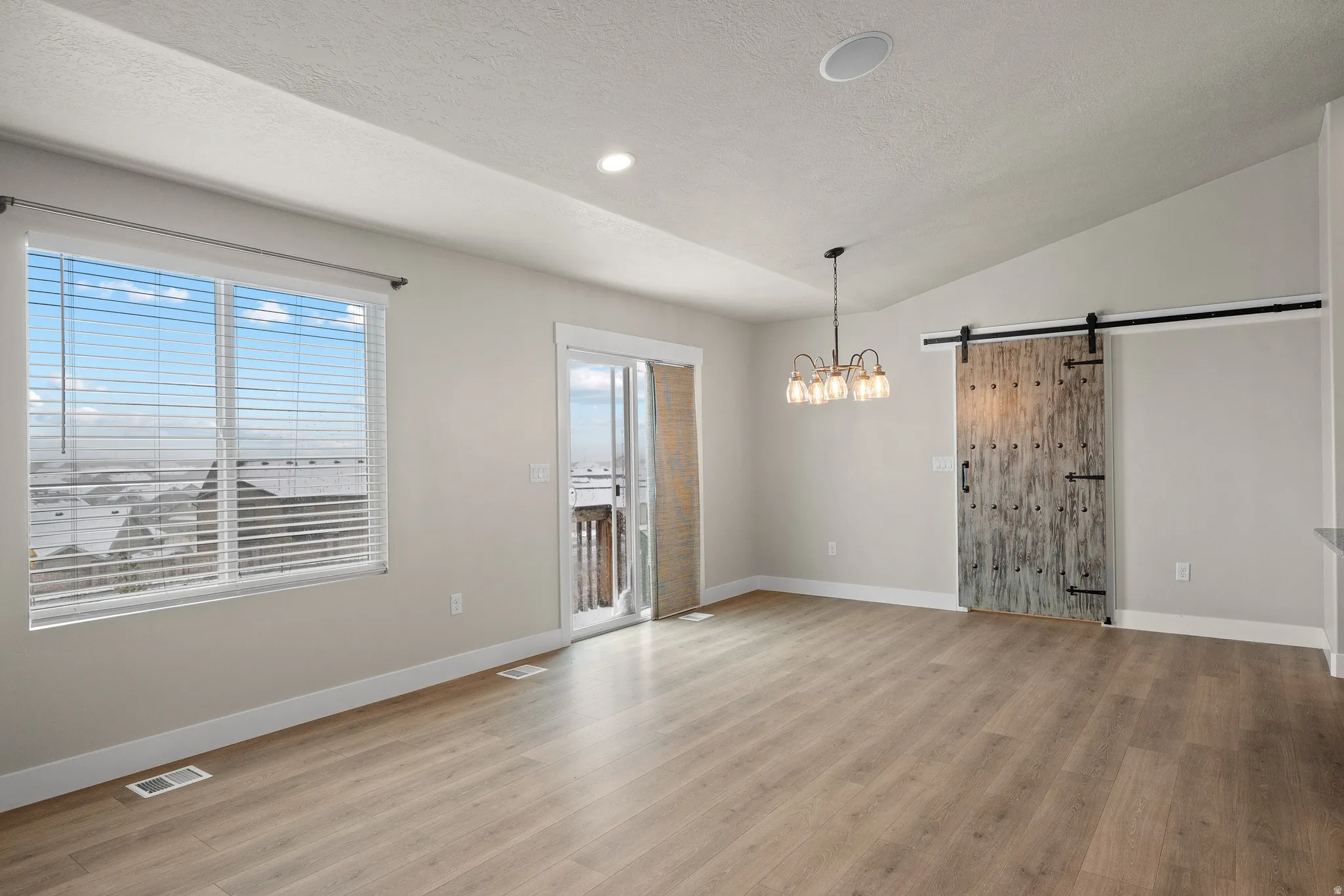 Unfurnished dining area featuring a barn door, light wood-style floors, and a chandelier