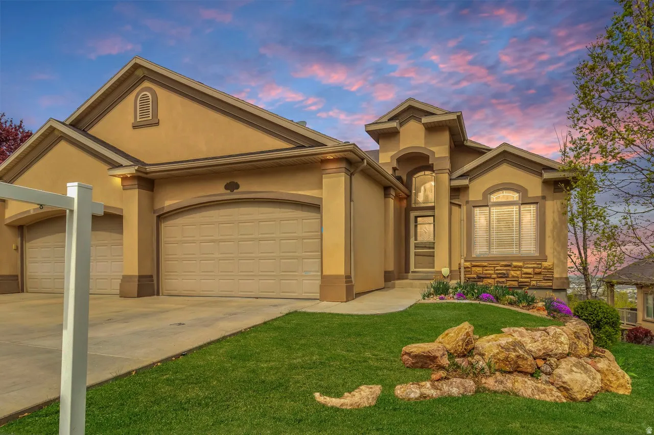 View of front facade featuring a garage, concrete driveway, stucco siding, and a lawn