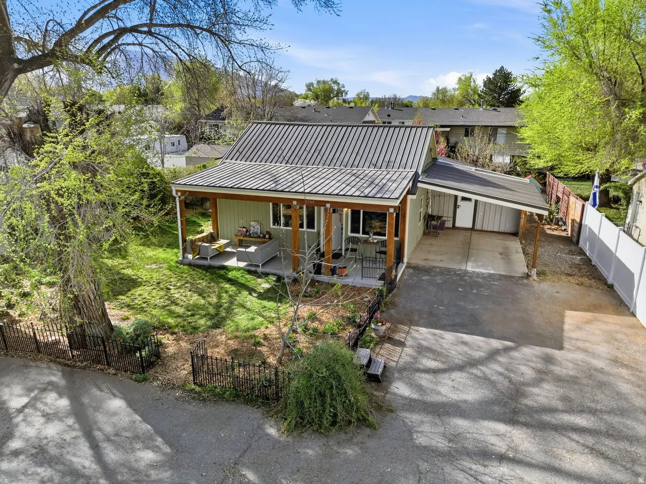 View of front of house with a covered patio, an attached carport, a metal roof, and driveway