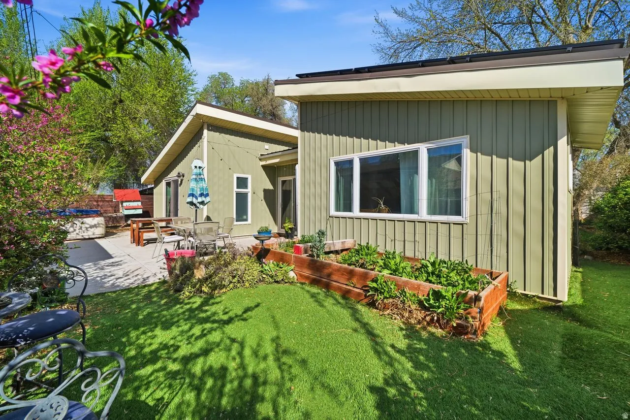 Rear view of property featuring a yard, a garden, a patio area, and outdoor dining area
