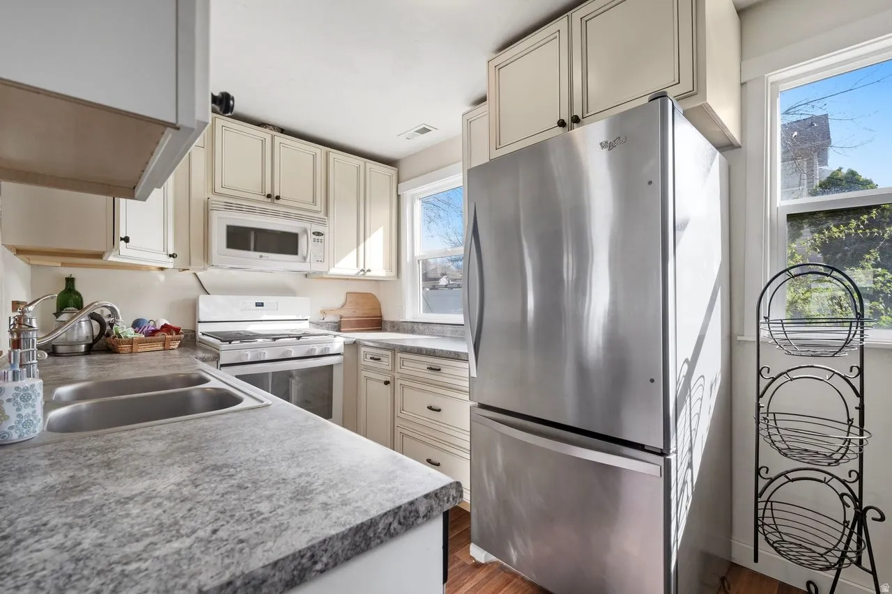 Kitchen with white appliances, cream cabinetry, light countertops, new gas oven/stove