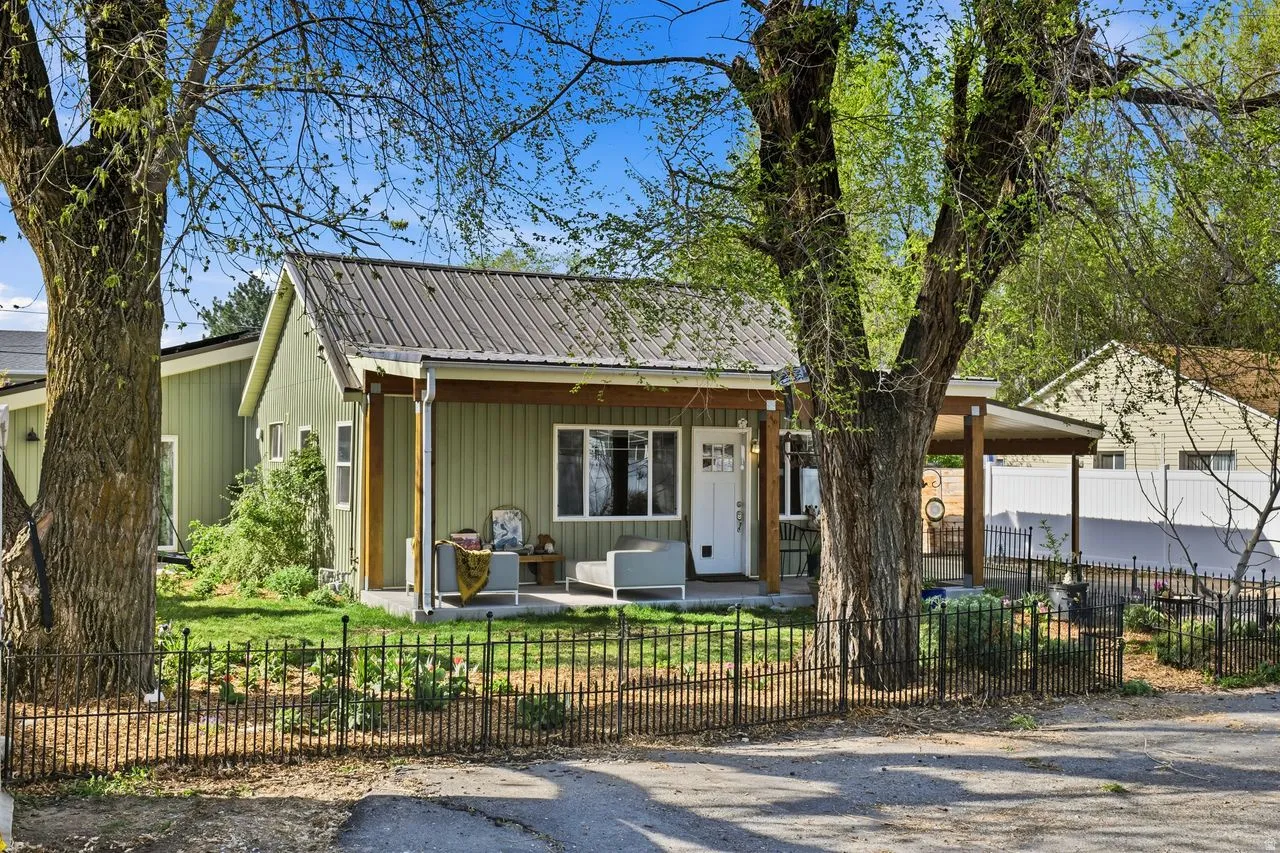 Chalet / cabin with a fenced front yard, a metal roof, covered porch, and board and batten siding
