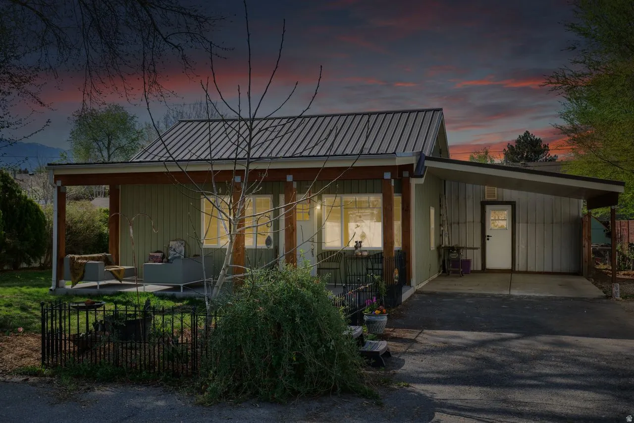 View of front of house with a carport, asphalt driveway, and a metal roof