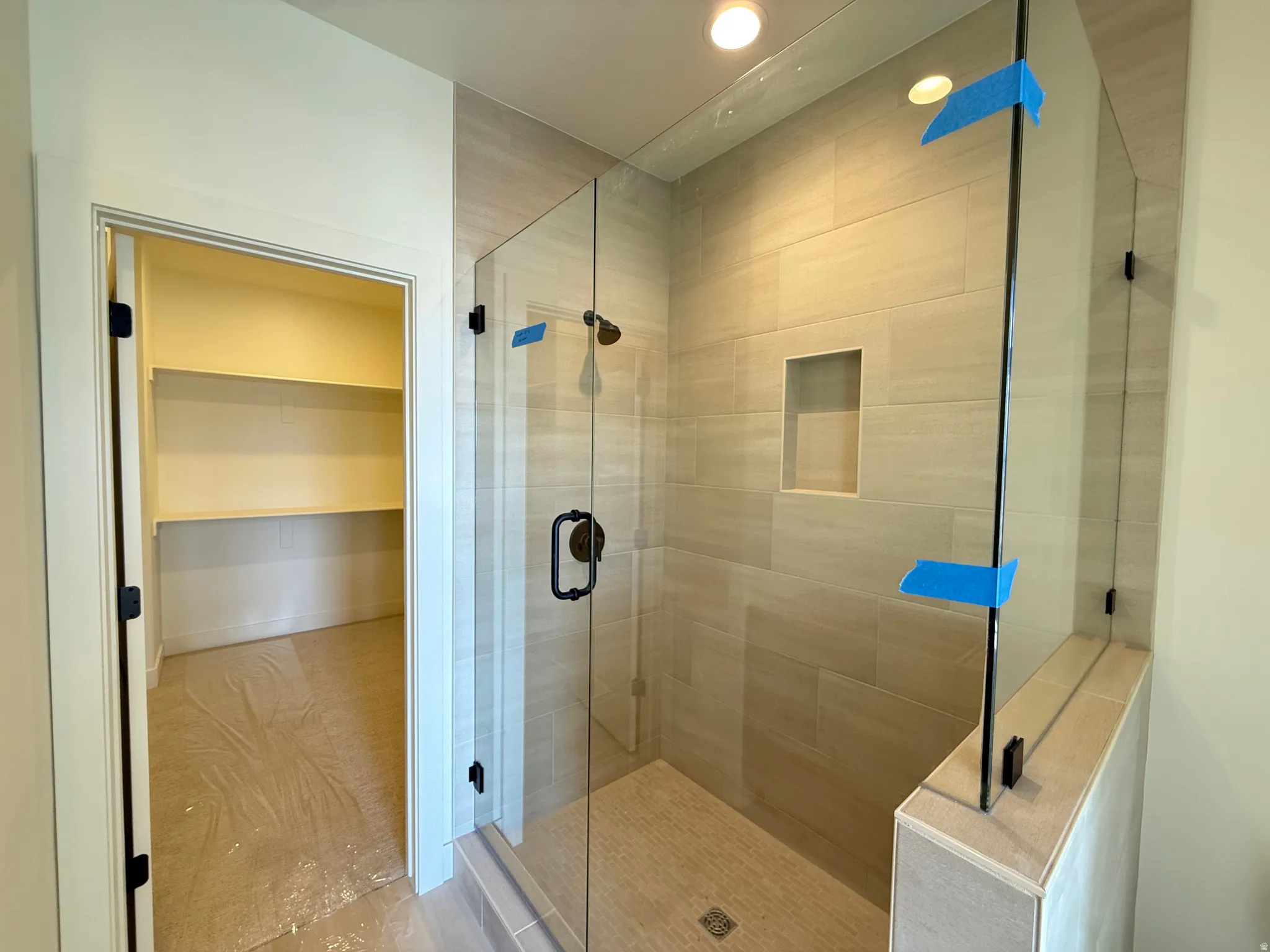 Primary Bathroom featuring a tall full Euro shower and tile to the ceiling, a walk in closet, and recessed lighting
