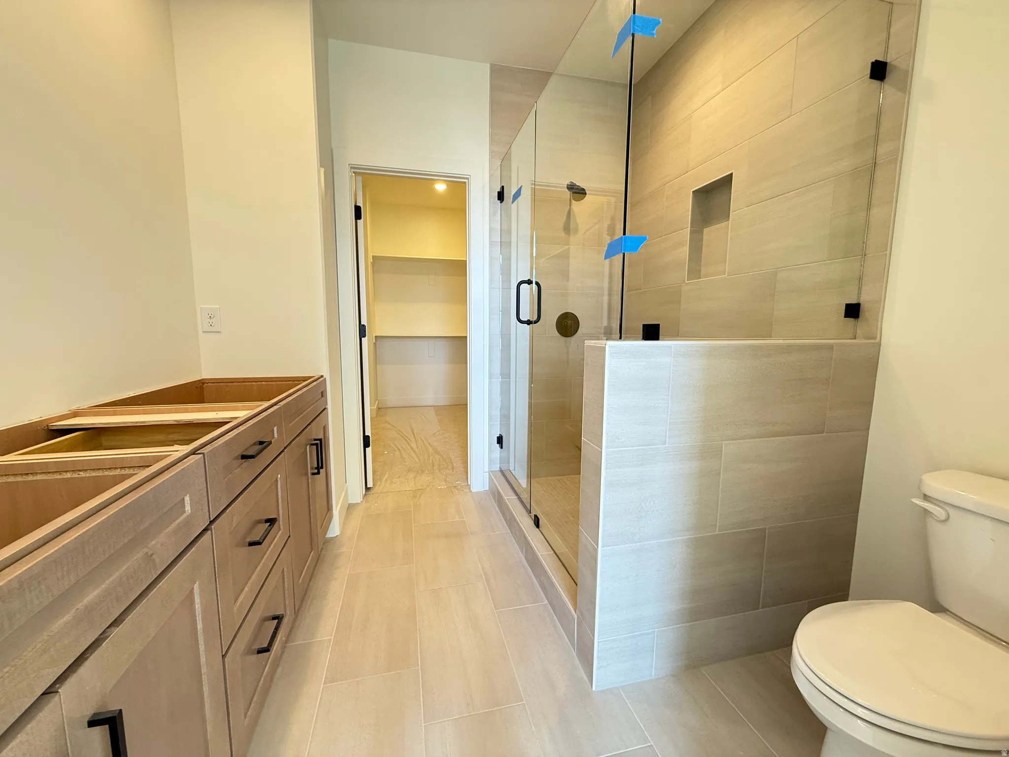 Primary bath featuring double vanity, a shower stall, and a spacious closet