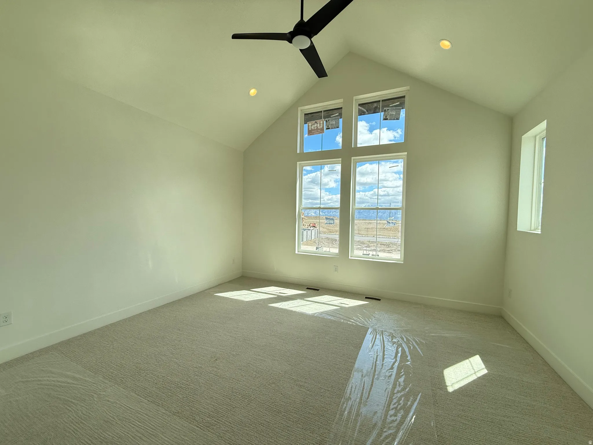 Primary suite with vaulted ceilings, ceiling fan, carpet flooring, and recessed lighting