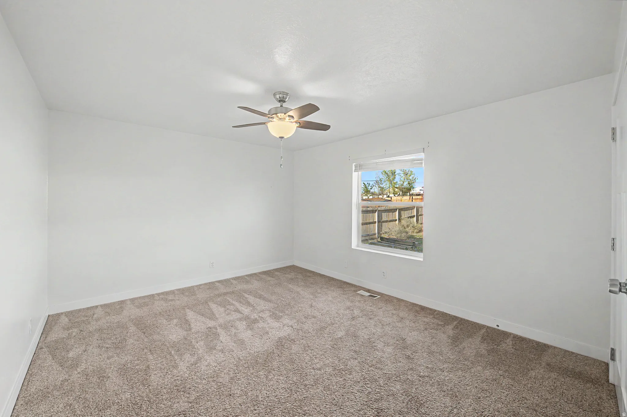 Carpeted spare room with baseboards and ceiling fan