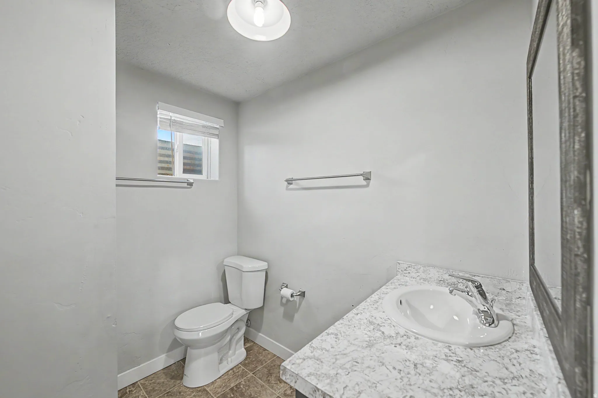 Half bath featuring vanity, dark tile patterned flooring, and a textured ceiling