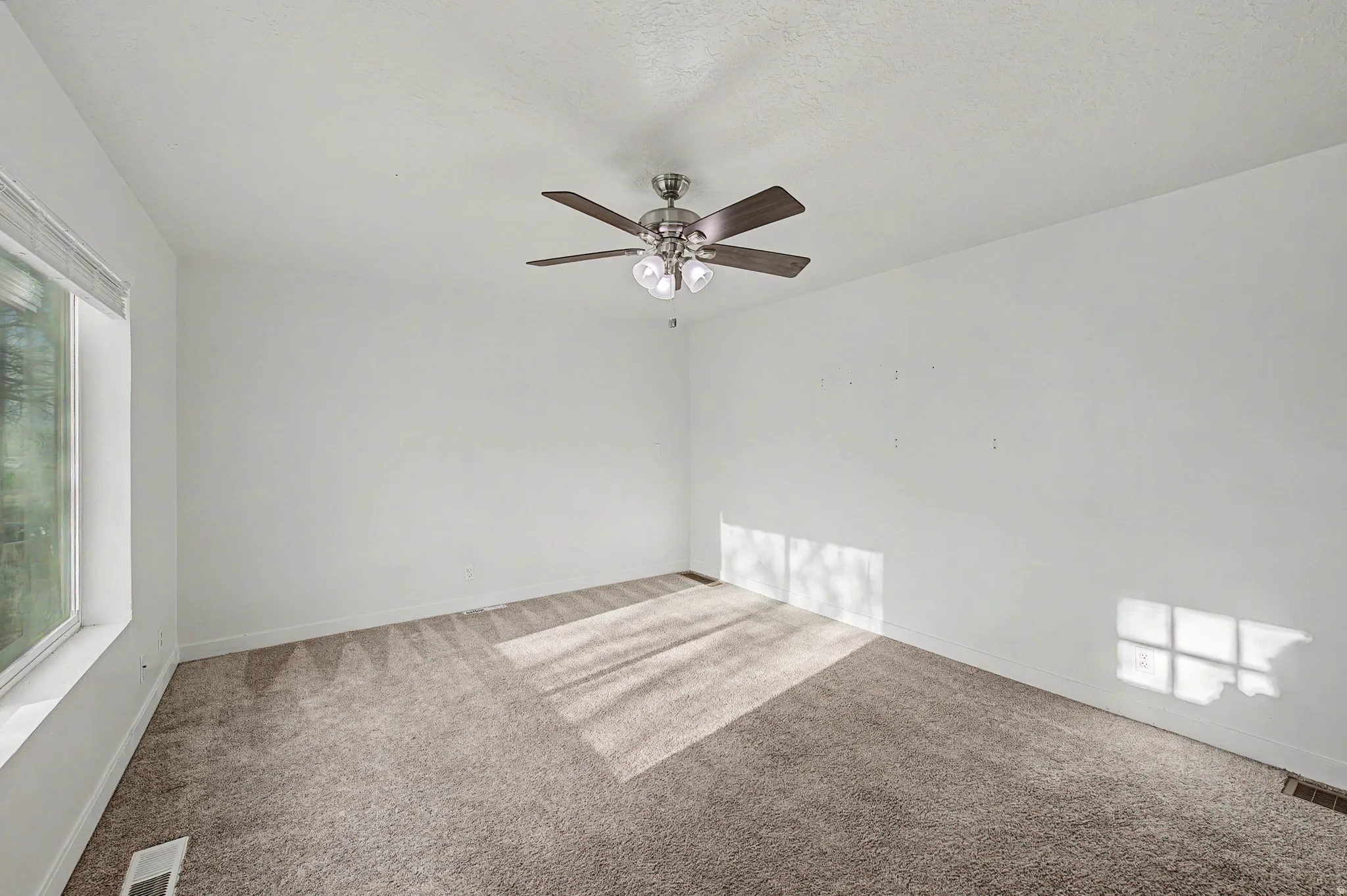 Carpeted empty room featuring a ceiling fan and baseboards