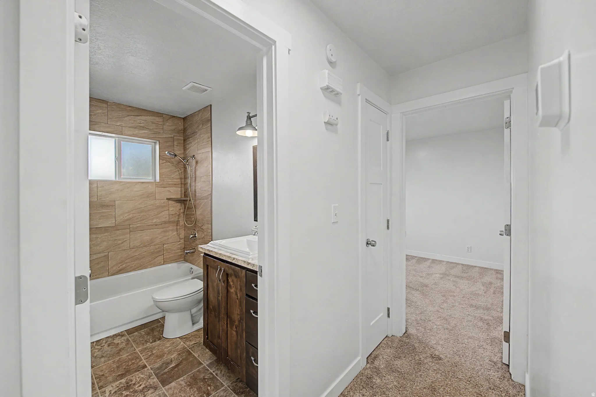 Full bathroom featuring vanity, tub / shower combination, dark colored carpet, and dark stone finish floors