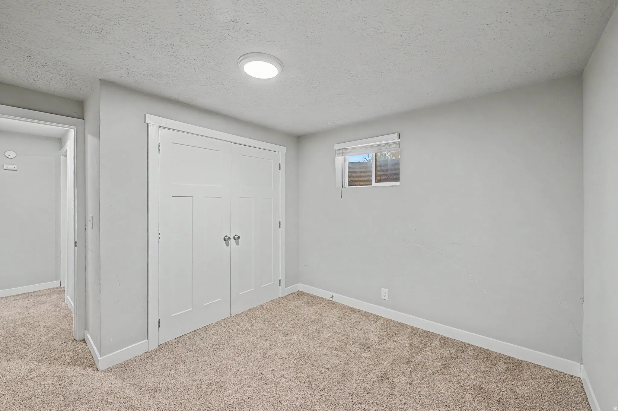 Unfurnished bedroom with a textured ceiling, light colored carpet, and a closet