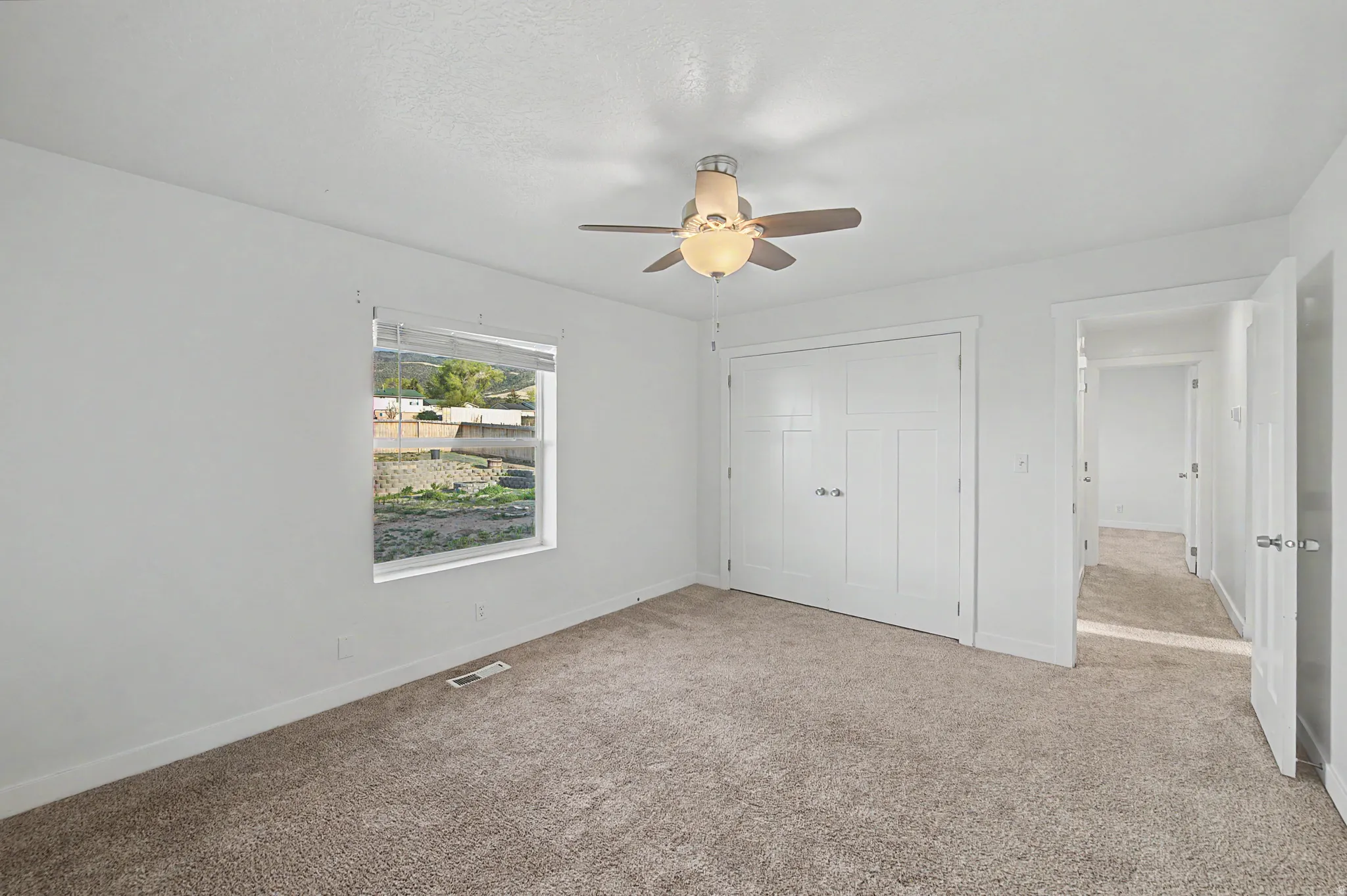 Unfurnished bedroom featuring light colored carpet, a closet, and ceiling fan