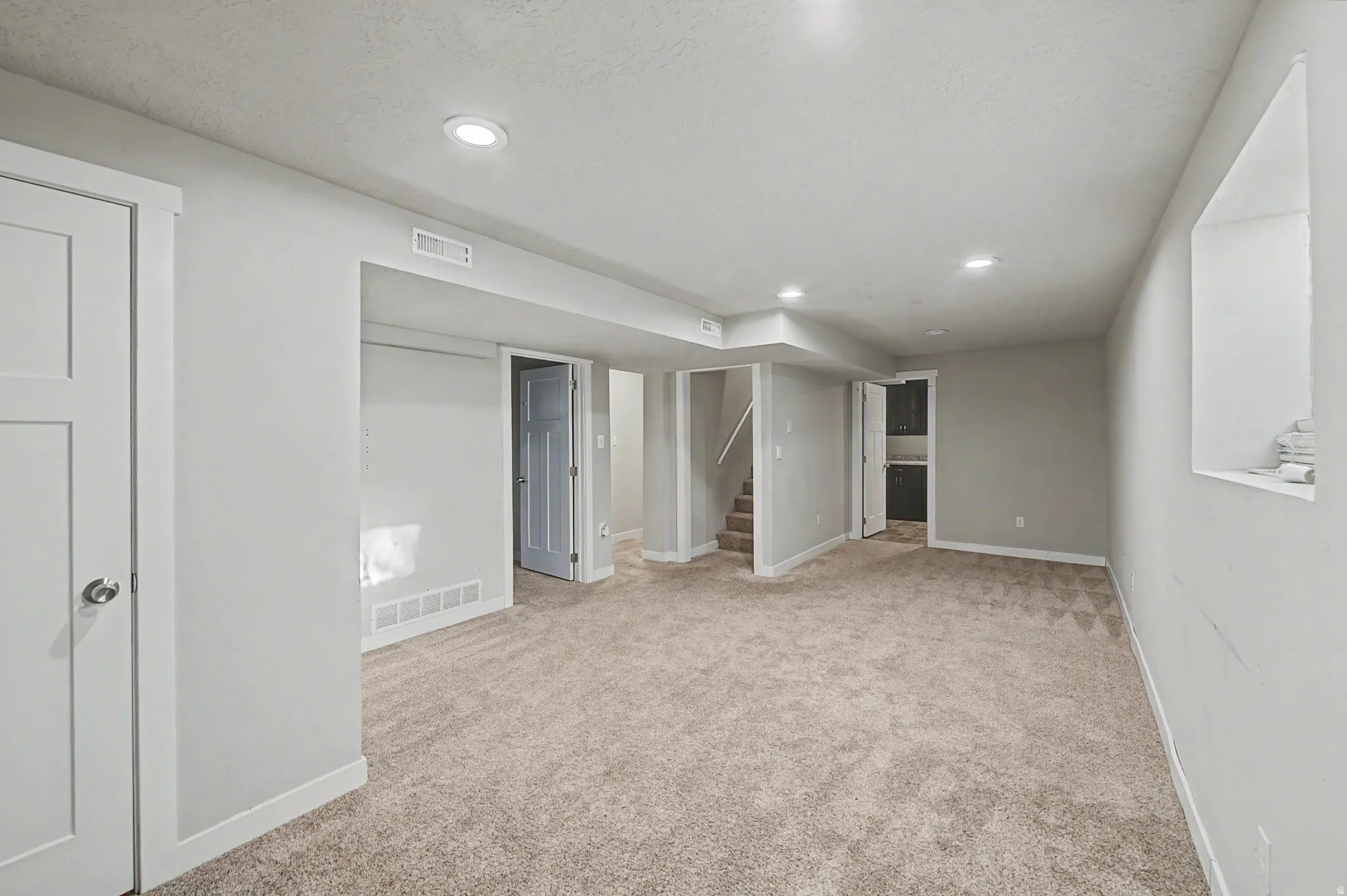 Finished below grade area featuring light colored carpet and recessed lighting
